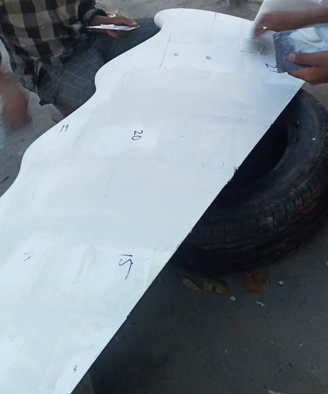 A numbered white template board for the blade curve, marked and cut on a tyre at the roadside at dusk.