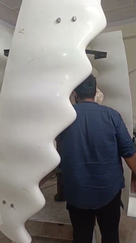 Full-size white blade shells standing in the workshop, a team member walking between them, back to camera.