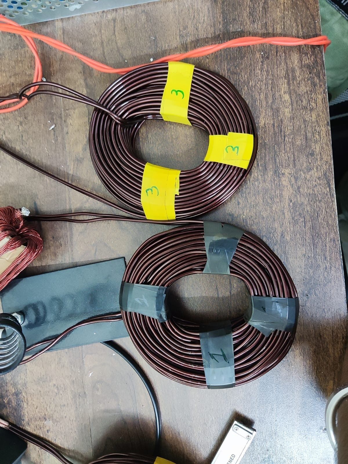 Two hand-wound copper coils on the bench, taped and numbered.