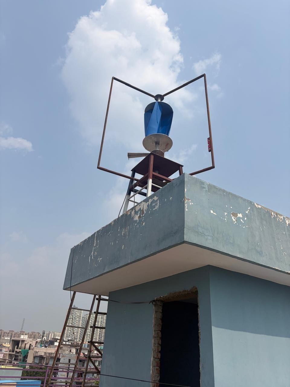 The inner rotor and stand frame fitted at the top of the steel stand on the rooftop parapet, outer blades not yet mounted, seen from below.